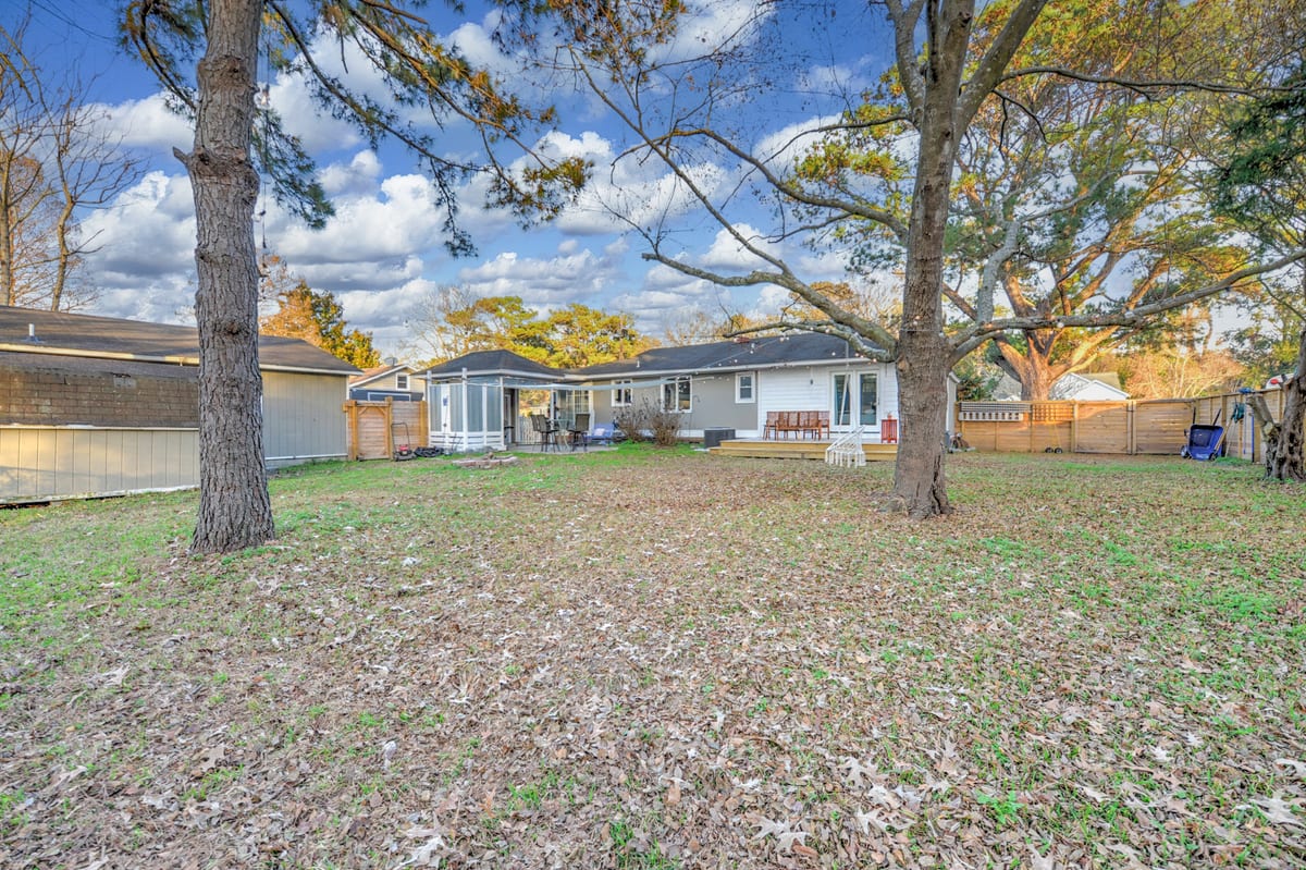 Wide back lawn with mature trees behind the house