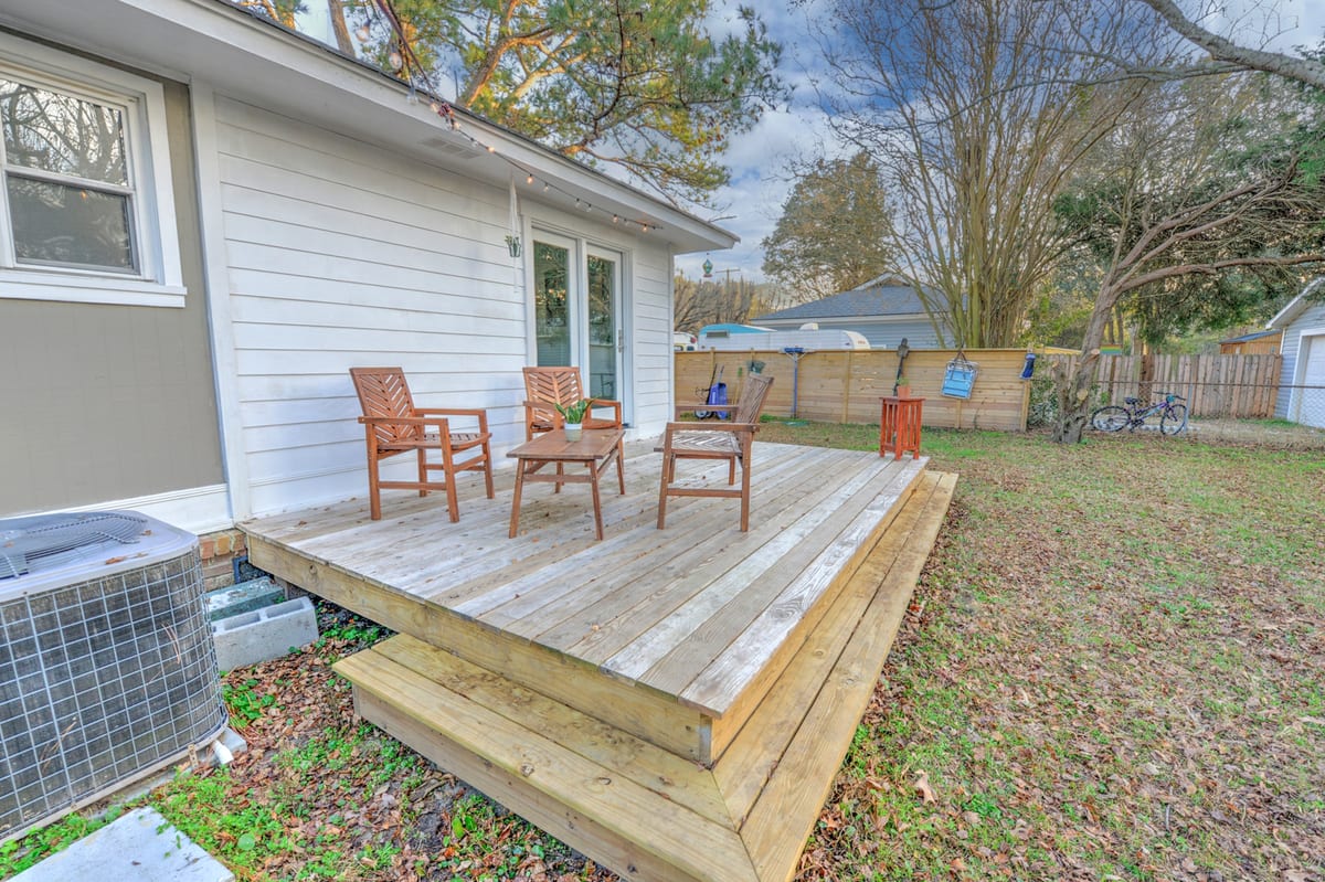 Wooden rear deck with three chairs, a low table, and string lights under the eaves