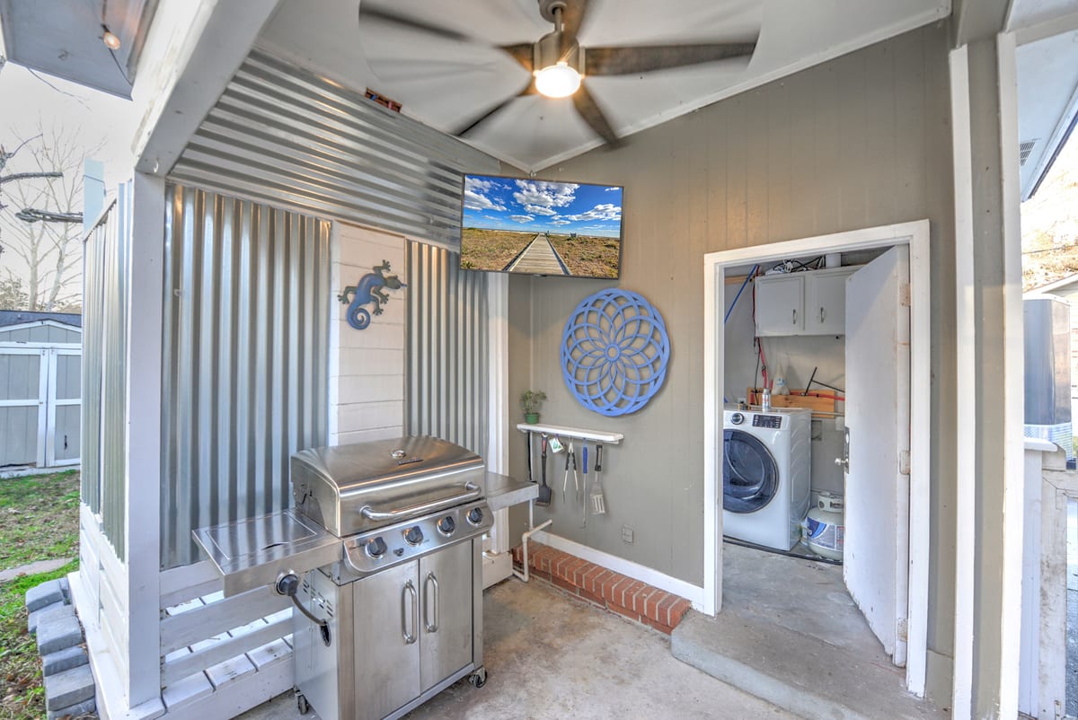 Covered patio with a gas grill and wall-mounted television
