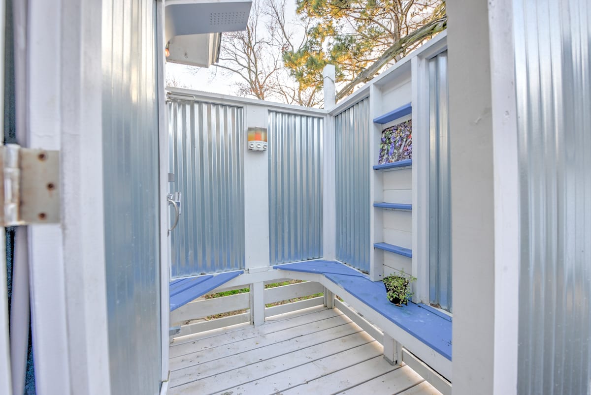 Outdoor shower enclosure with benches and shelves