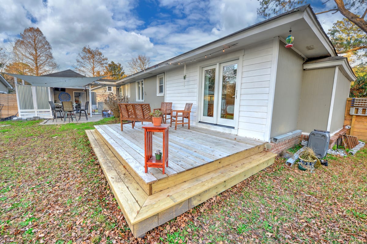 Rear deck with wooden chairs beside the house under a blue sky